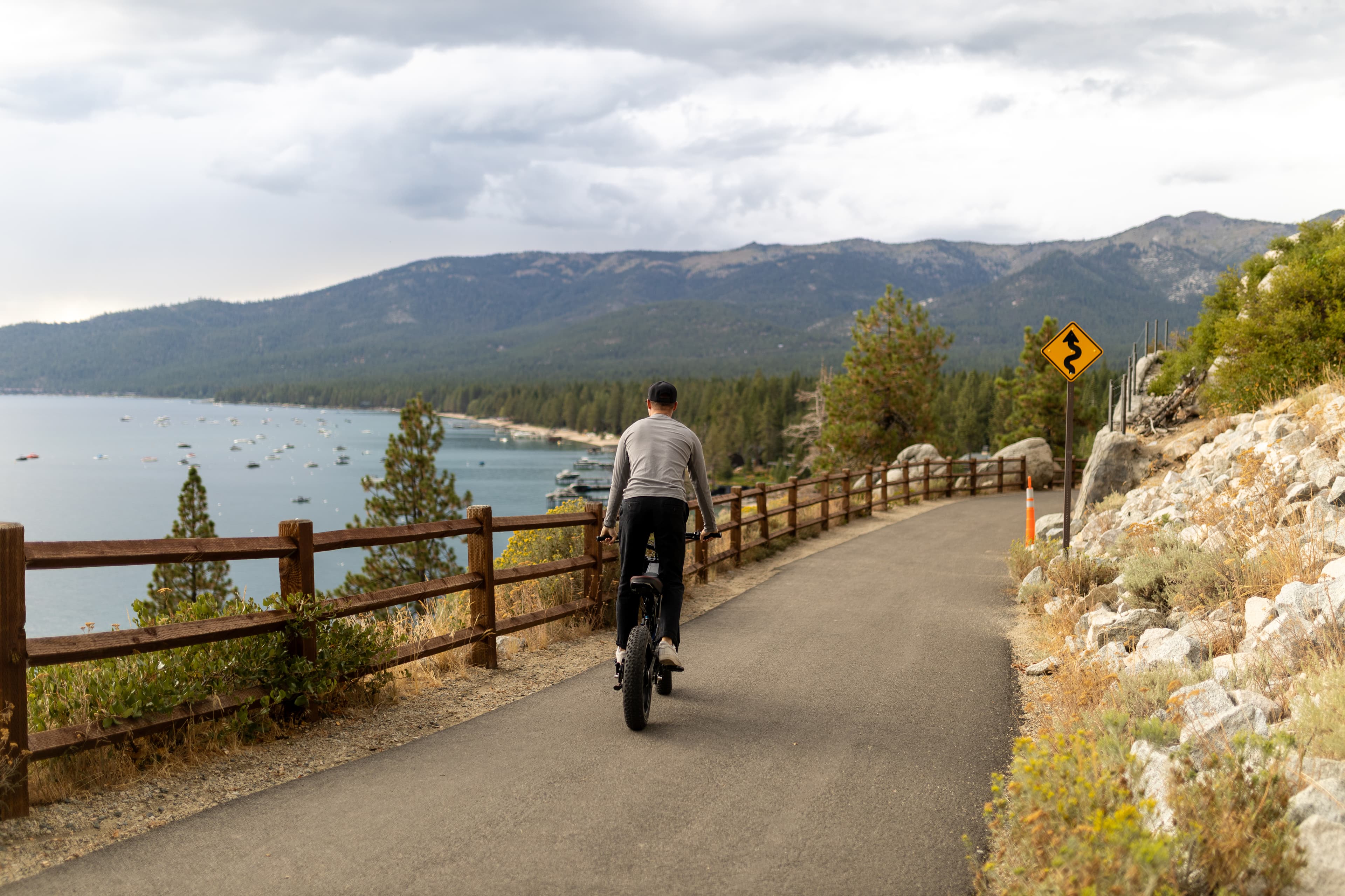 Surfline rider on a scenic Tahoe road with lake and mountain backdrop